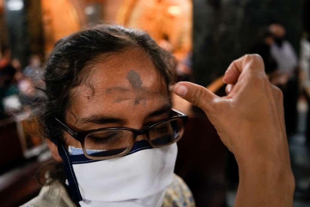 Señora aplicándose las cenizas para cumplir las medidas de bioseguridad en la Iglesia La Coromoto en Miércoles de Ceniza