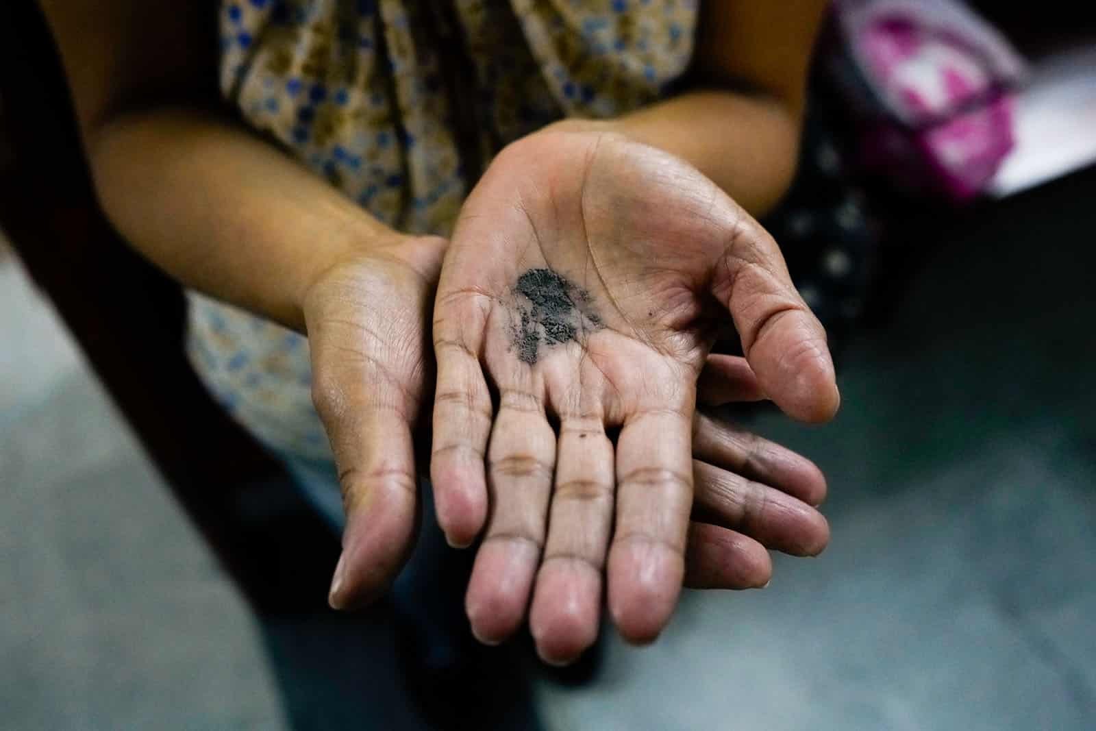 Señora con cenizas en la mano para aplicársela ella misma en la frente cumpliendo las medidas de bioseguridad en la Iglesia La Coromoto en Miércoles de Ceniza